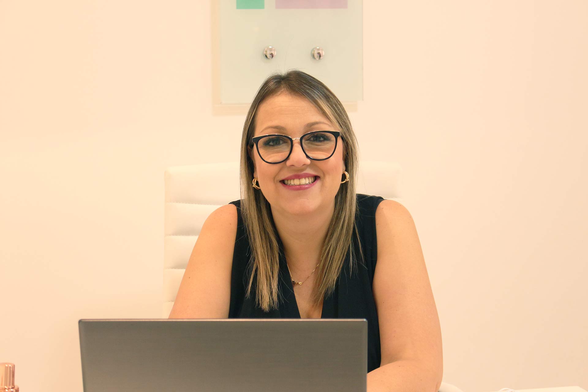 Dra. Adriana Couto na mesa do consultório, com o notebook aberto
